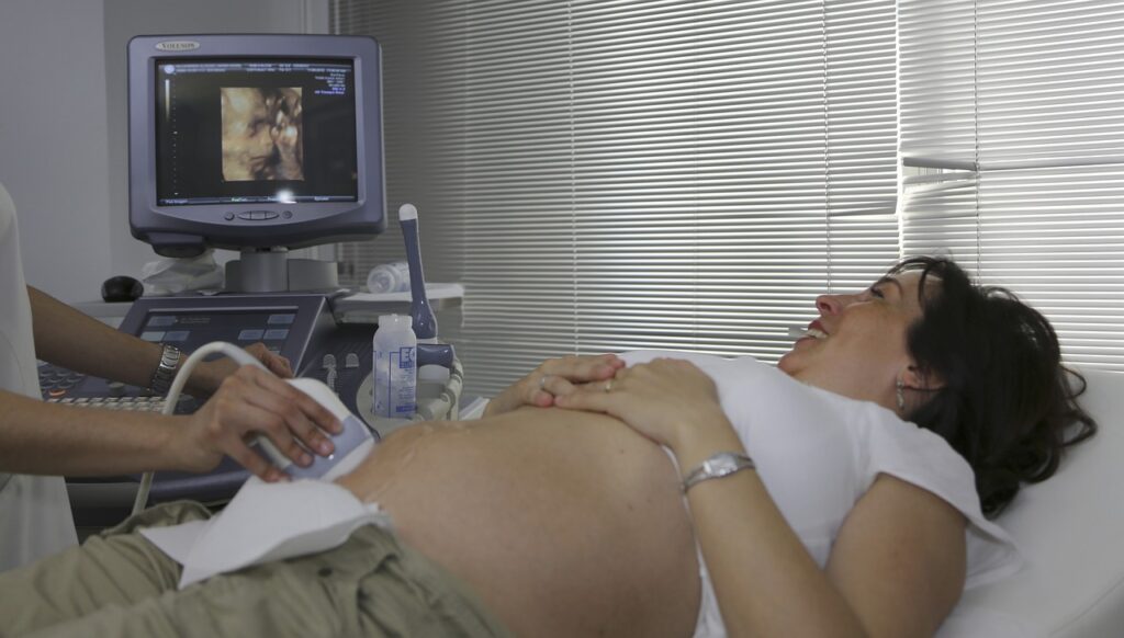 A pregnant woman in the hospital watching tv.